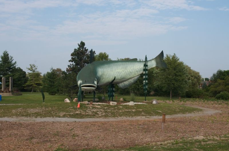 A large fish statue in a park with trees in the background