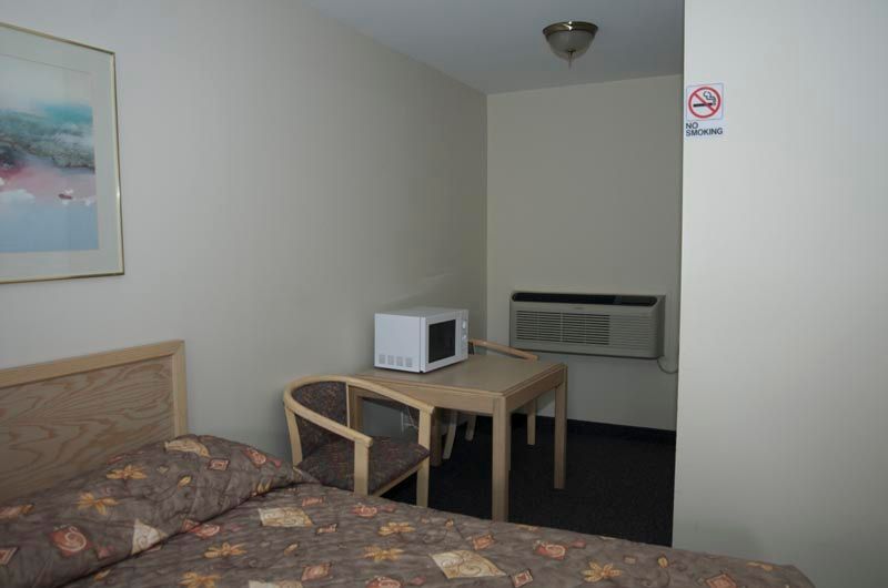 A hotel room with a bed , table , chair and microwave.