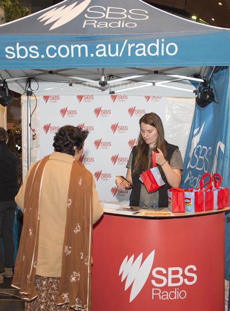 A woman is standing in front of a sbs radio booth