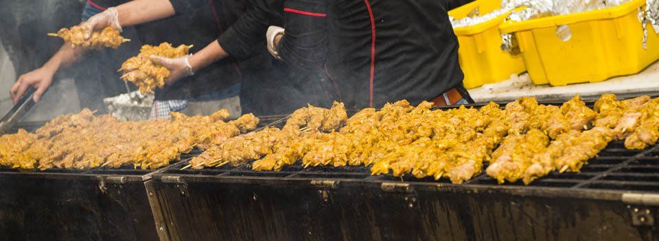 A group of people are cooking food on a grill.