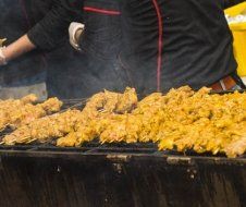 A person is cooking chicken on a grill.