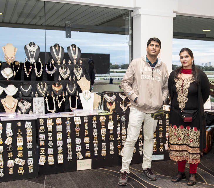 A man and a woman are standing in front of a display of jewelry
