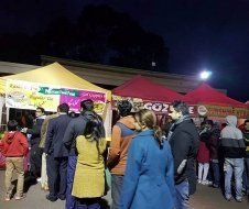 A group of people are standing in line at a food stand at night.