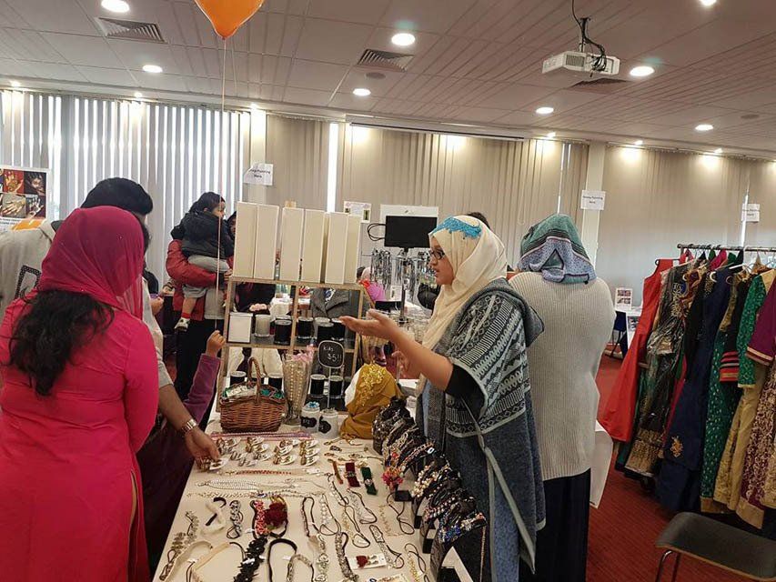 A group of women are standing around a table at a market.
