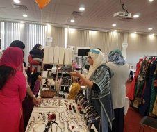 A group of women are standing around a table looking at jewelry.