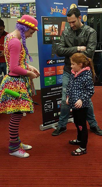 A woman in a clown costume is standing next to a little girl.