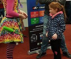 A girl in a colorful dress is standing next to a girl in a blue jacket.