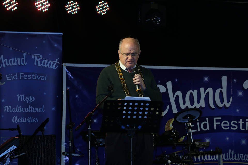 A man is standing at a podium holding a microphone.