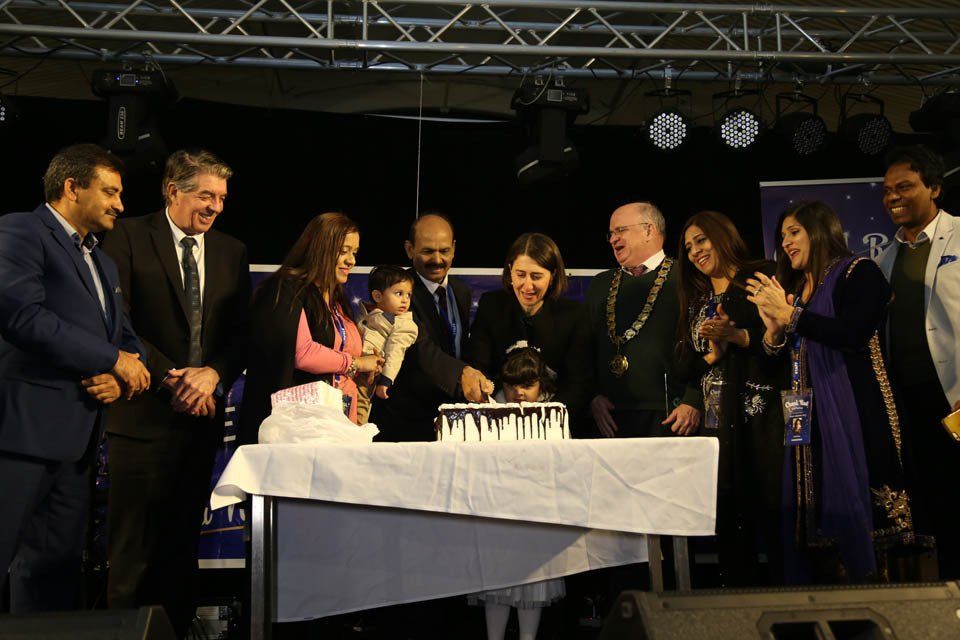 A group of people are standing around a table cutting a cake.