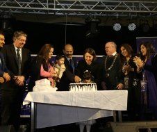 A group of people are standing around a table cutting a cake.