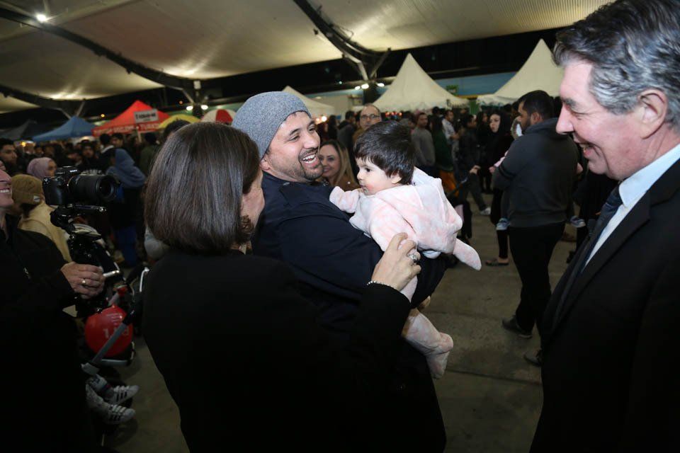 A woman is holding a baby in her arms while talking to a man in a suit.