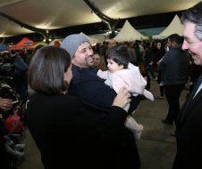 A woman is holding a baby in her arms while talking to a man.