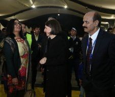 A group of people are standing in a room talking to each other.