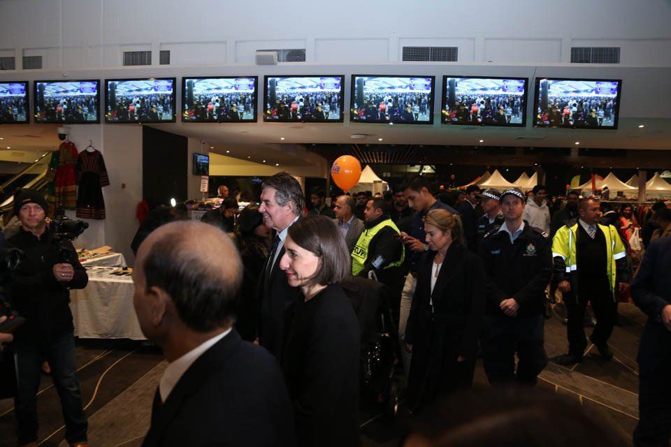 A group of people standing in front of a wall of televisions.