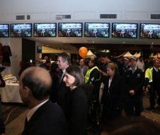 A group of people are standing in front of a wall of televisions.