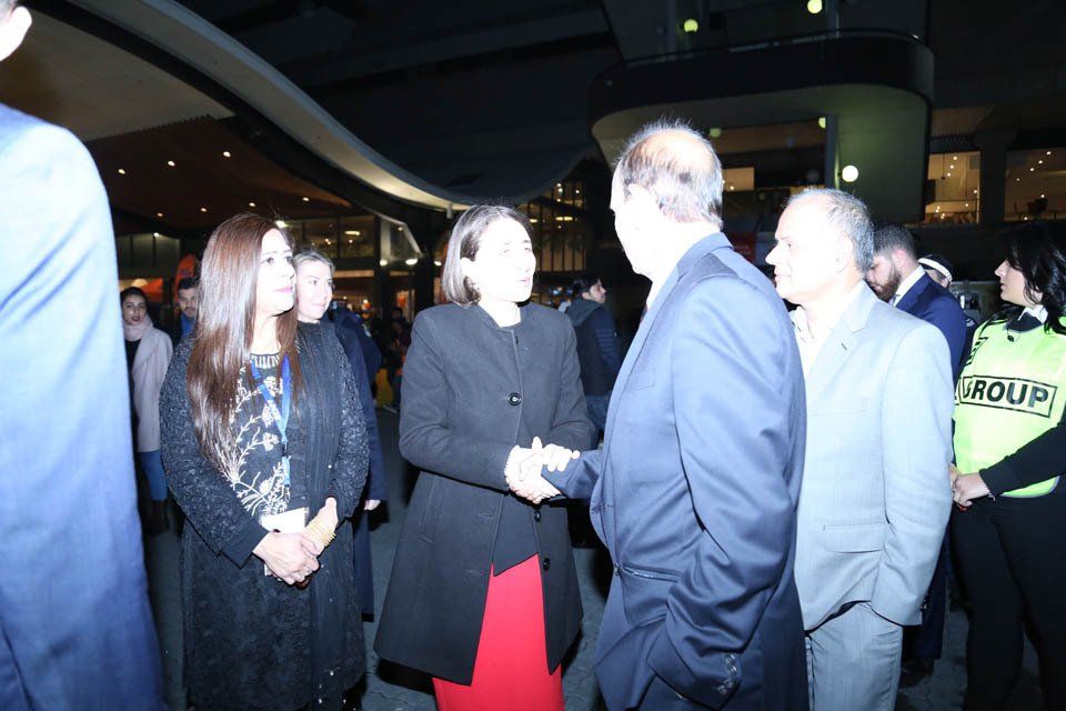 A group of people are standing in a room and one of them is wearing a yellow shirt that says arquby