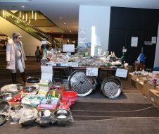 A woman is standing in front of a table filled with bowls and pans.