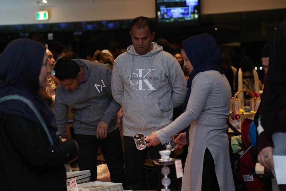 A group of people are standing around a table and one of them is wearing a calvin klein hoodie.