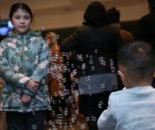 A group of children are playing with soap bubbles in a room.