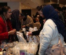 A group of people are standing around a table looking at necklaces.