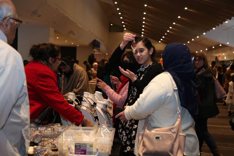 A group of people are standing around a table at a market.
