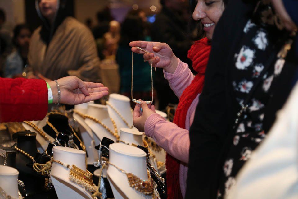A woman is taking a picture of a necklace on a mannequin.