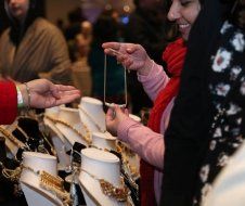 A woman is looking at a necklace on a mannequin in a store.