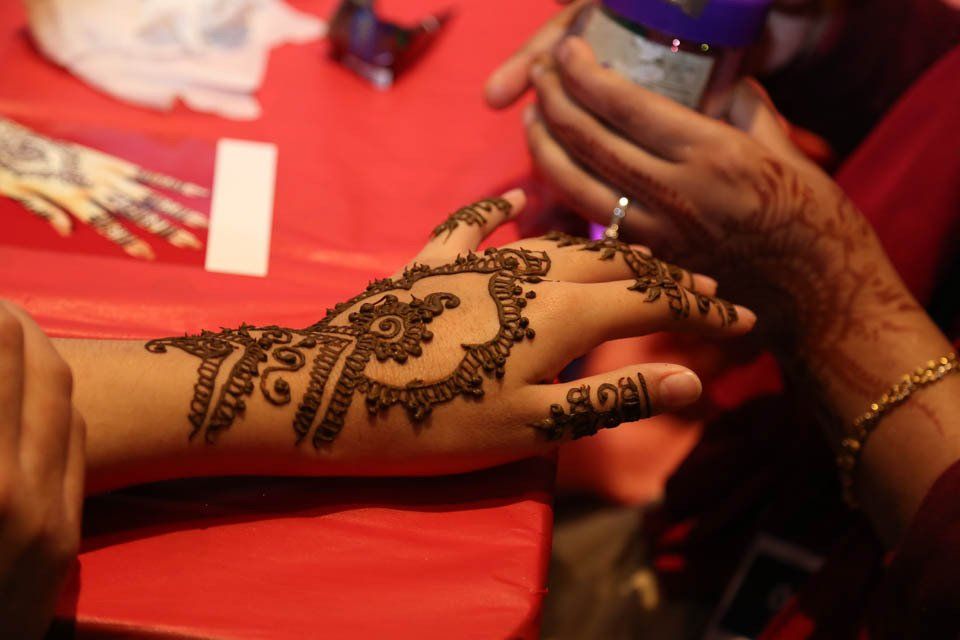 A woman is getting a henna tattoo on her hand