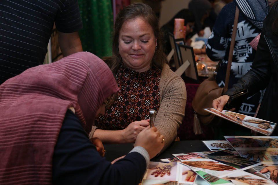 A woman in a head scarf is sitting at a table with other people.
