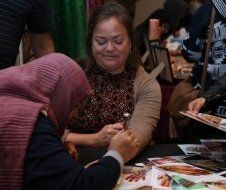 A woman is sitting at a table with a spoon in her hand.