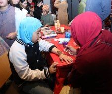 A woman is painting a child 's hand with henna.