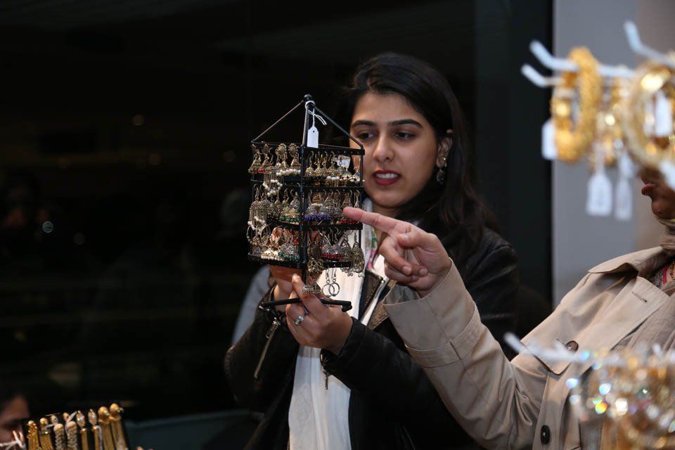 A woman is pointing at a display of jewelry in a store.