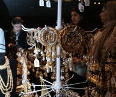 A woman is looking at a display of gold jewelry.