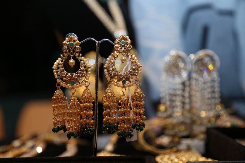 A pair of gold earrings with green beads are on display in a store.
