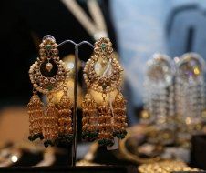 A pair of gold earrings are sitting on a stand in a store.