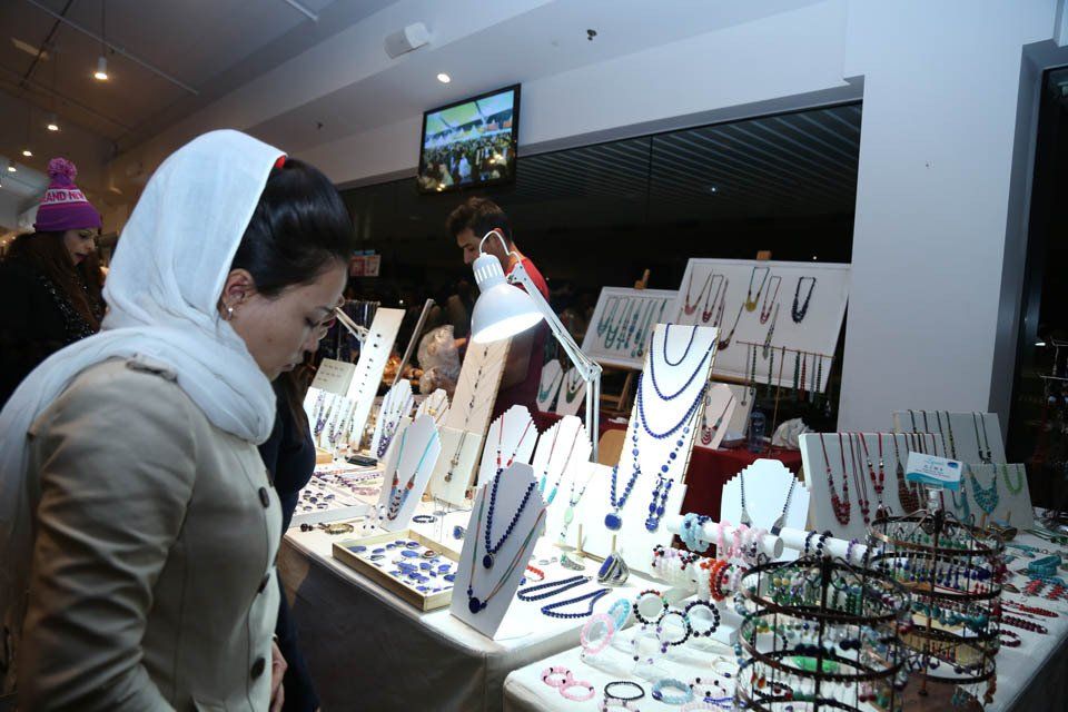 A woman is looking at a table full of jewelry