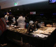 A group of people are standing around a table with jewelry on it.