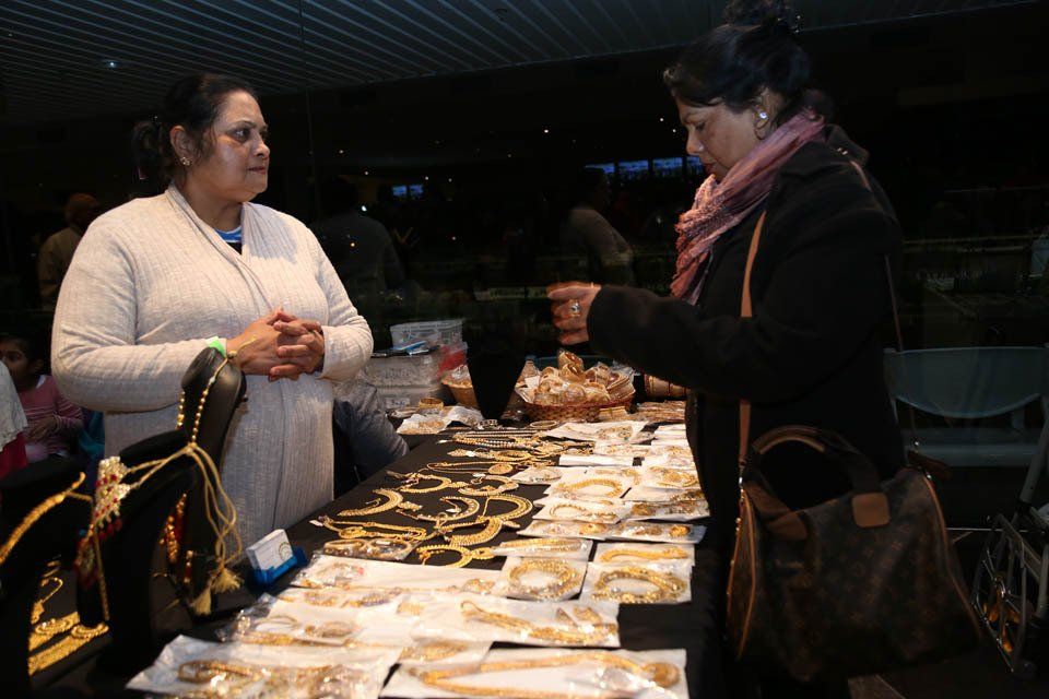 Two women are standing at a table looking at jewelry.