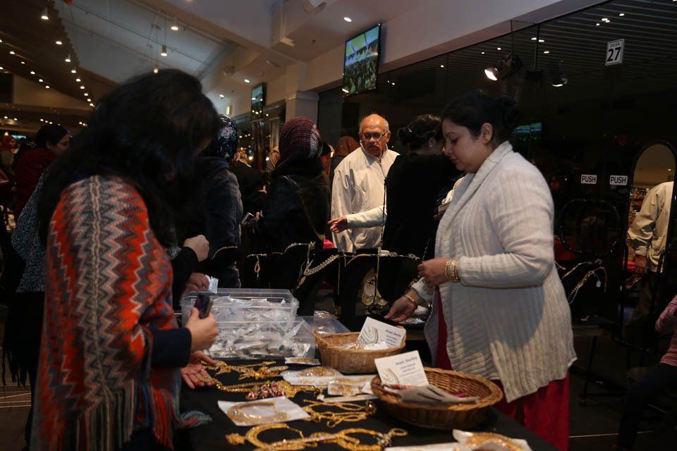 A group of people are standing around a table looking at jewelry.