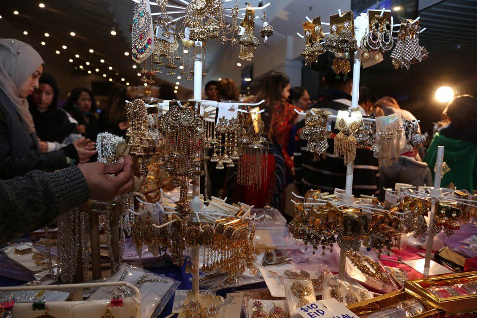 A group of people are looking at jewelry at a market.