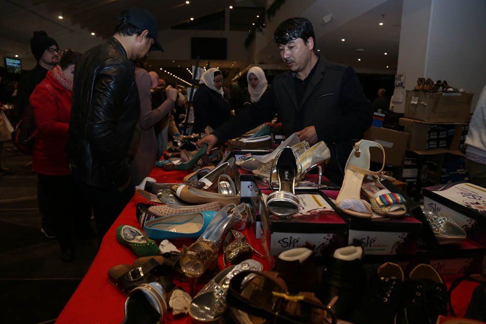 A group of people are looking at shoes on a table.