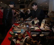 A group of people are looking at shoes on a table.
