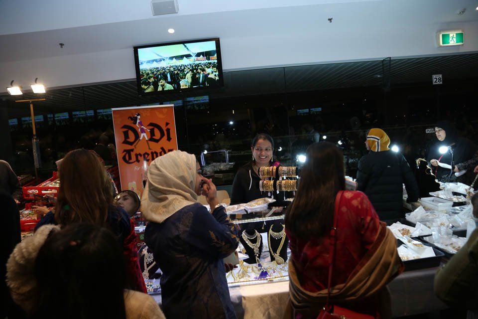 A group of people are standing around a table with a sign that says ' dadi trend ' on it