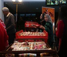 A group of people are standing around a table full of food.