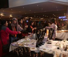 A group of people are standing around a table looking at jewelry.