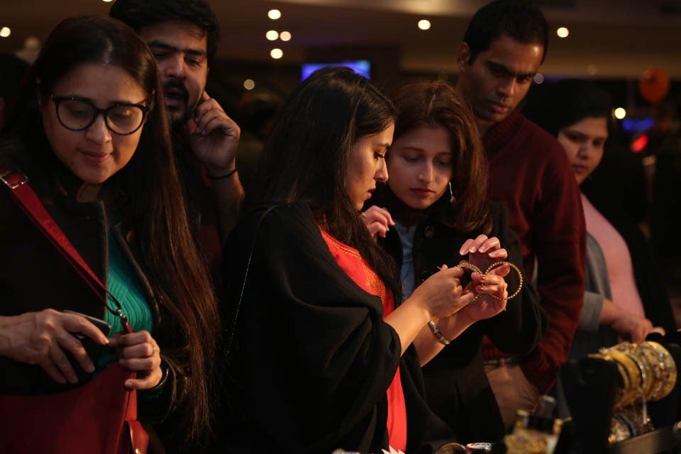 A group of people are standing around a table looking at jewelry.