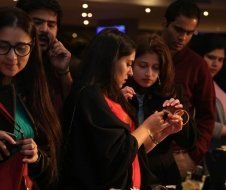 A group of people are standing around a table looking at their phones.