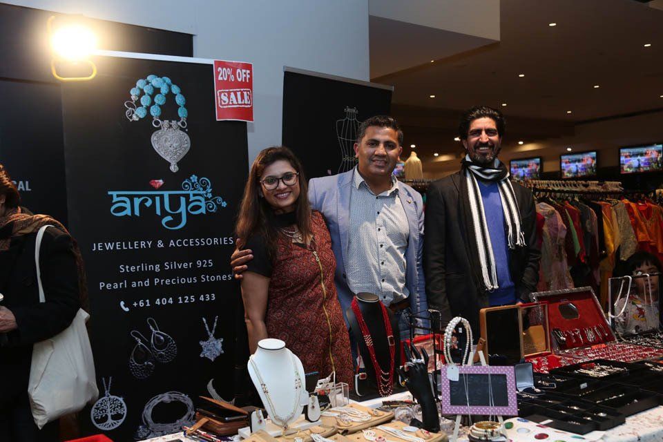 A group of people are posing for a picture in front of a table with jewelry on it.