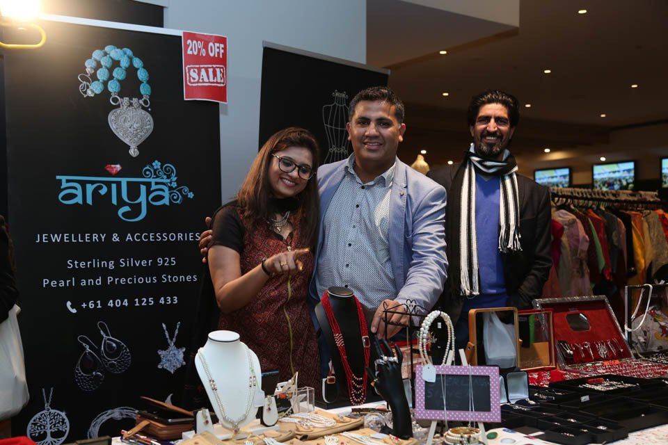 Three people are standing in front of a table with jewelry on it.