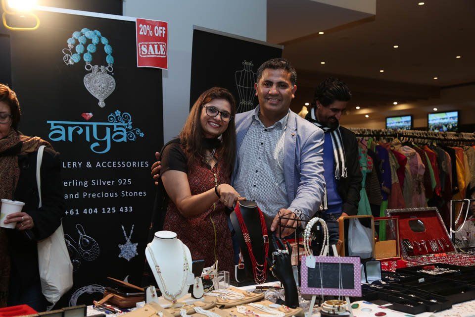 A man and a woman are standing in front of a table with jewelry on it.